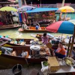 Mercato galleggiante in Thailandia con barche piene di cibo di strada e ombrelloni colorati