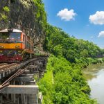 Treno sulla storica Ferrovia della Morte a Kanchanaburi, Thailandia, su ponte di legno lungo il fiume Kwai